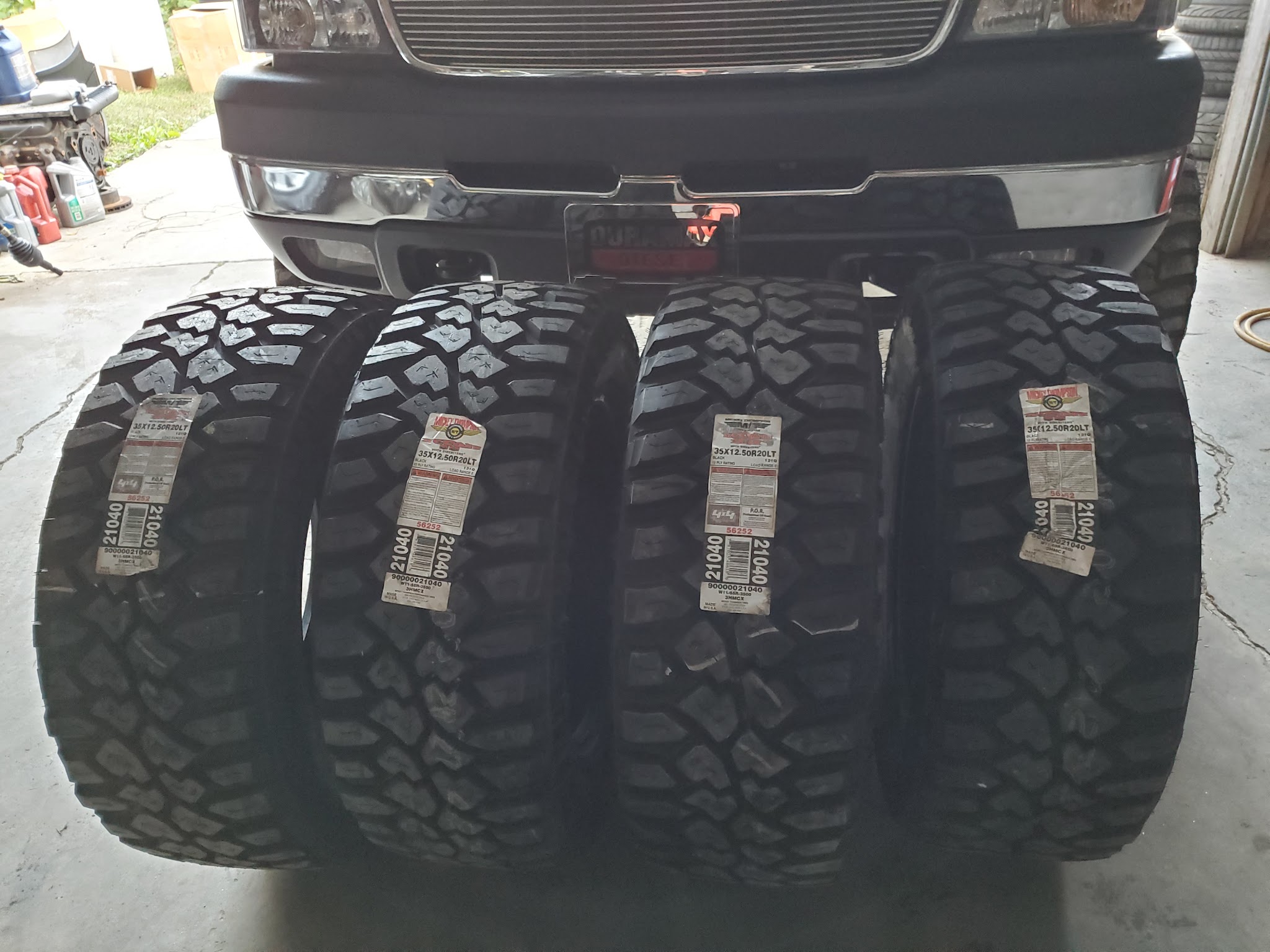 A set of four new off-road tires lined up behind a truck