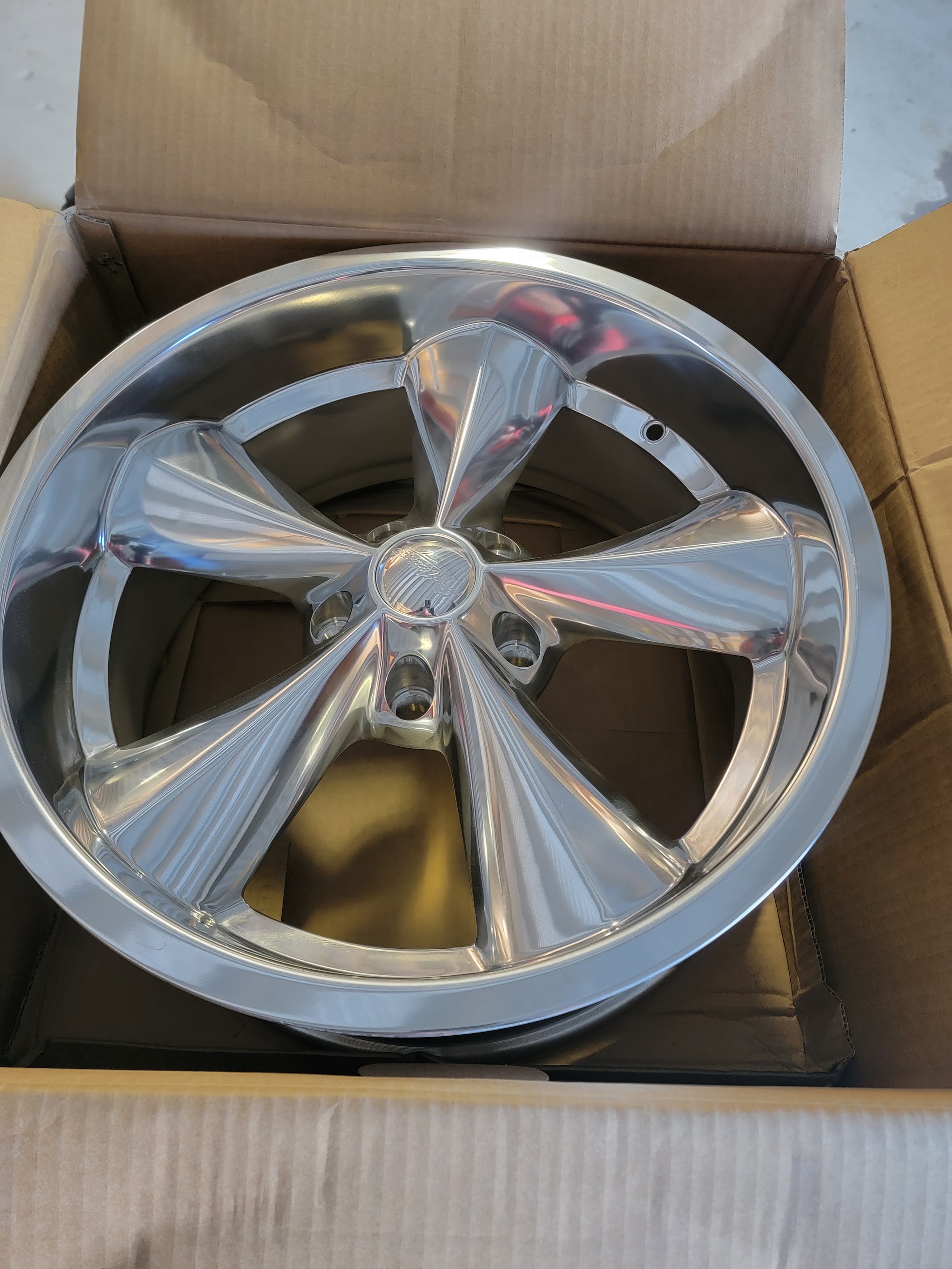A polished five-spoke wheel boxed up and ready